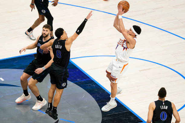 Devin Booker of the Suns shoots as Josh Green of the Mavericks defends during the second half at American Airlines Center in Dallas, Texas.