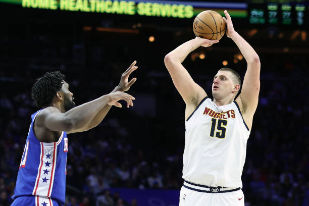 Jokic shooting over Embiid during Nuggets vs. 76ers game at Wells Fargo Center in Philadelphia.