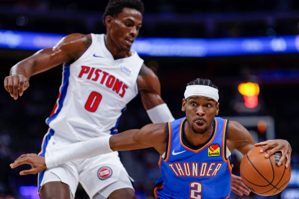 Shai Gilgeous-Alexander of the Thunder dribbles the ball against Jalen Duren of the Detroit Pistons in the first quarter of a game at Little Caesars Arena.