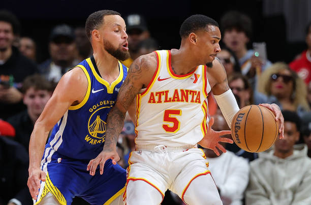 Stephen Curry defends against Dejounte Murray of the Hawks during a game at State Farm Arena in Atlanta, Georgia.